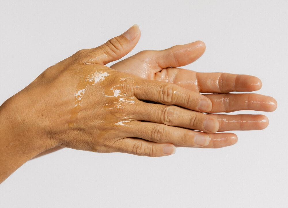 A woman rubbing Dr Tanya Holy Basil Face Serum together in her hands. 