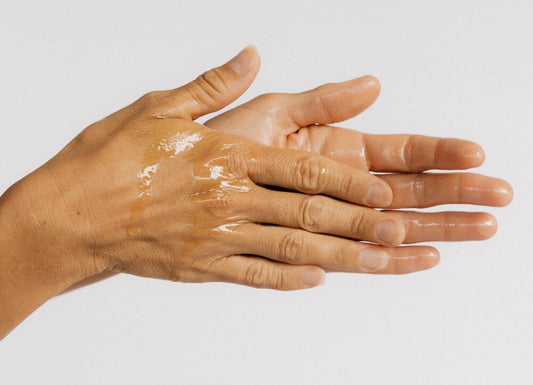 A woman rubbing Dr Tanya Holy Basil Face Serum together in her hands. 