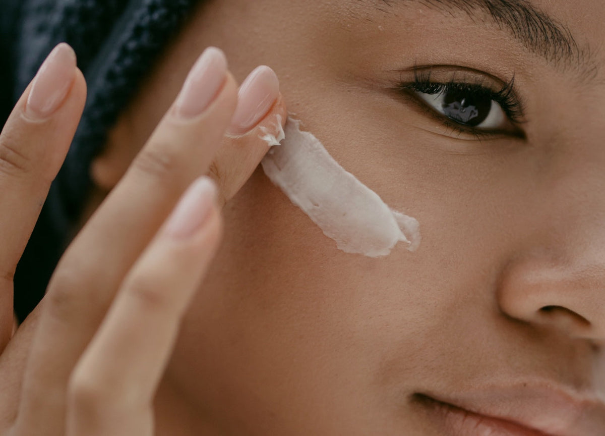Lady applying moisturiser to her cheek bone